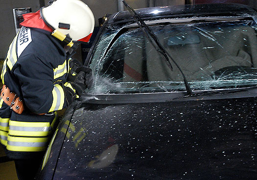 Brandmand der skærer med glasskærer i Rescue i forrude på bil